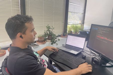 Joven latino centado frente a laptop en desarrollo web