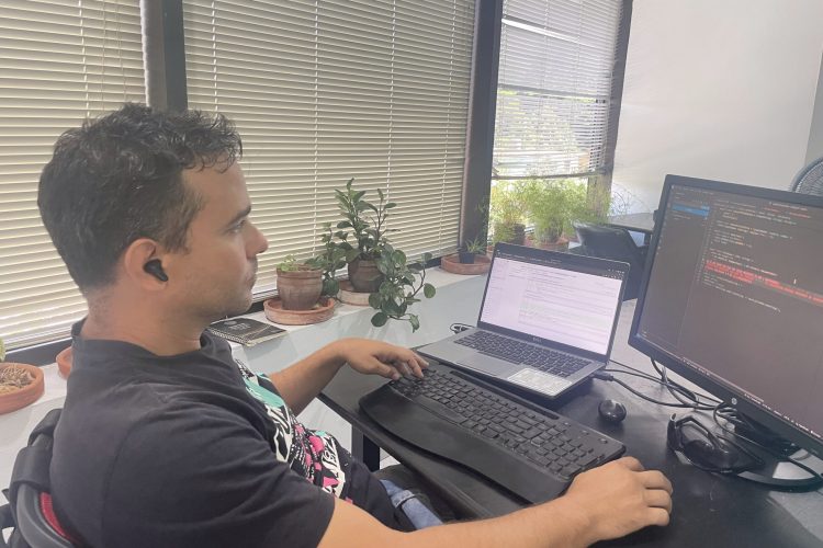 Joven latino centado frente a laptop en desarrollo web